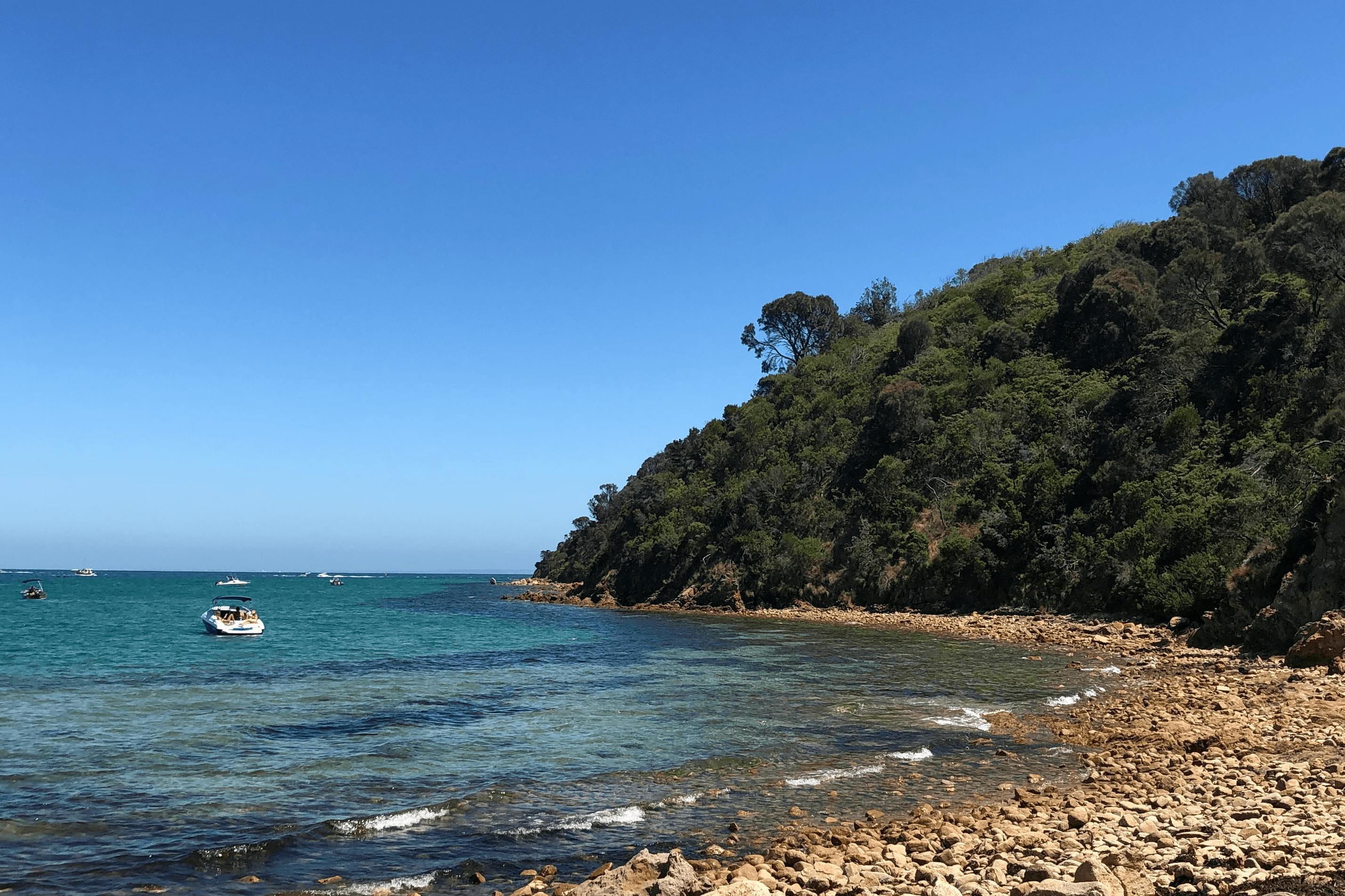 A small cove beach with blue waters and blue sky.